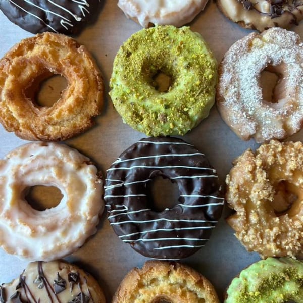 Assortment of Joe Donut's donuts, including chocolate, pistachio, powdered sugar, and glazed varieties.