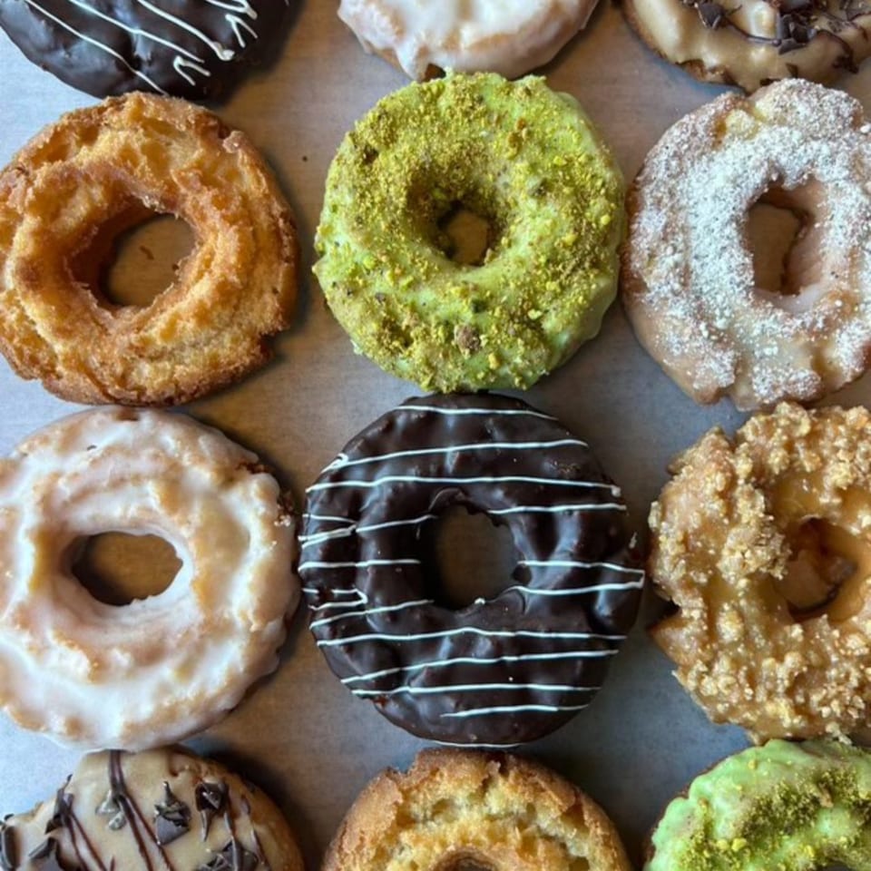 Assortment of Joe Donut's donuts, including chocolate, pistachio, powdered sugar, and glazed varieties.