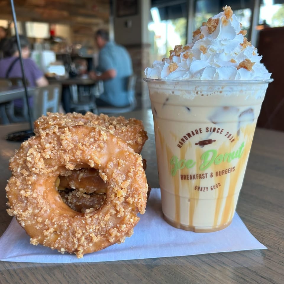 Three Joe Donut donuts with crumb topping and an iced coffee with whipped cream and caramel drizzle.