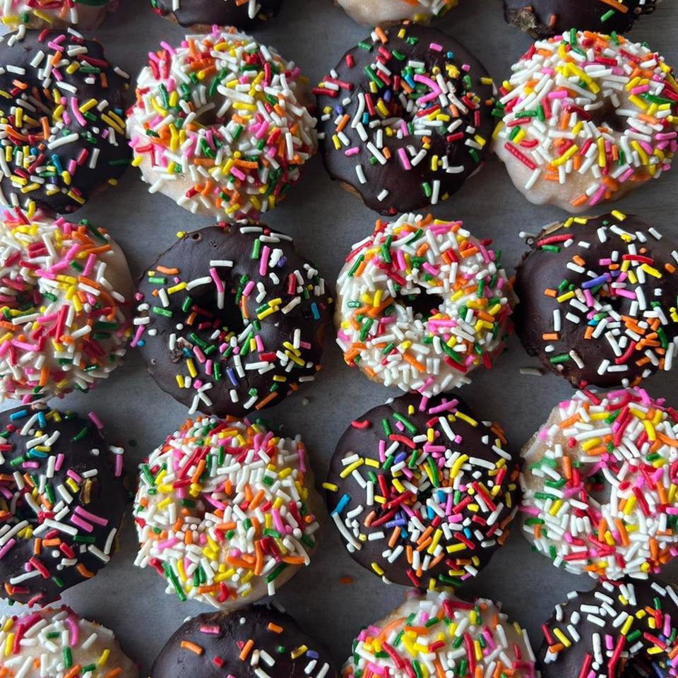 Rows of Joe Donut's chocolate and vanilla sprinkle donuts, showcasing colorful toppings.