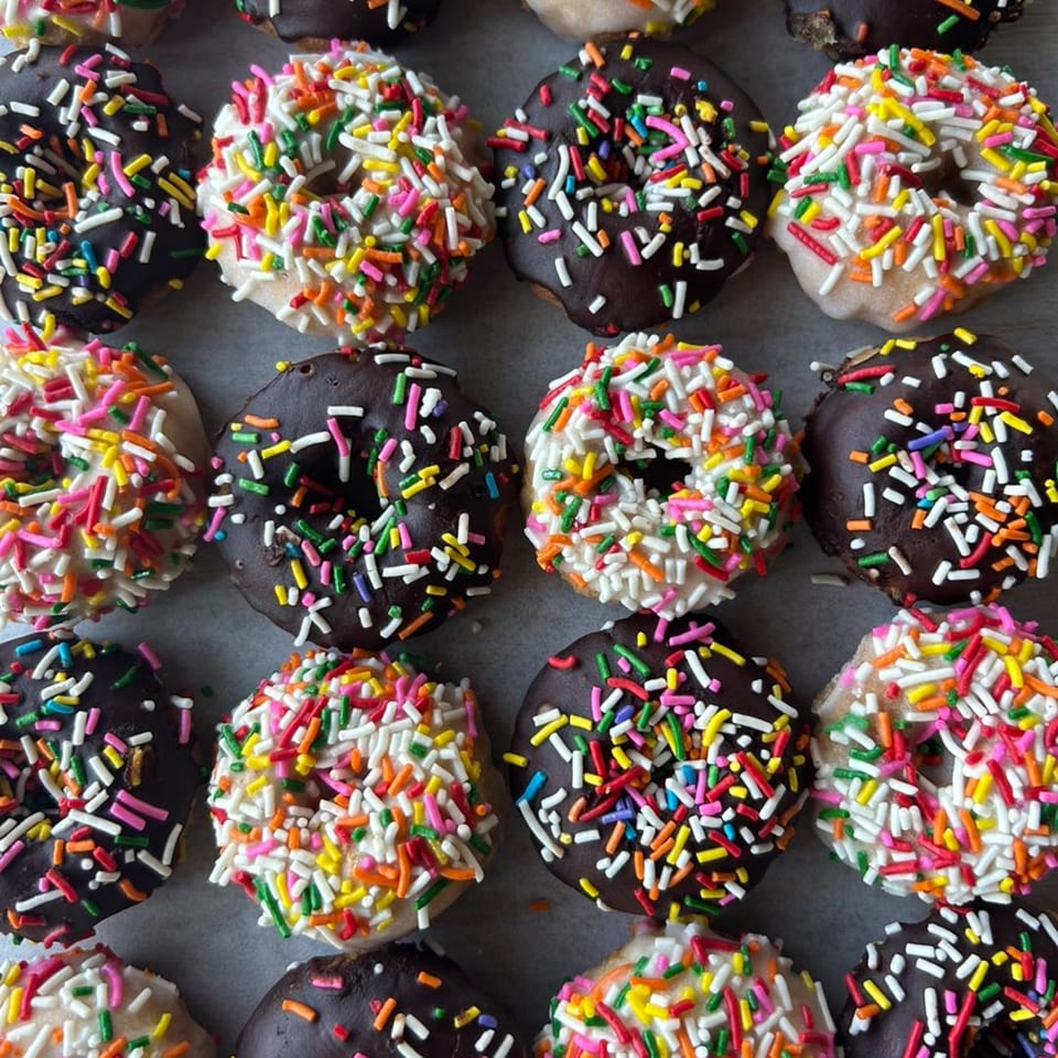 Rows of Joe Donut's chocolate and vanilla sprinkle donuts, showcasing colorful toppings.