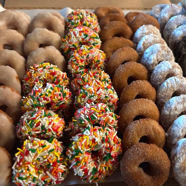A box of Joe Donut mini donuts with various toppings including sprinkles, glaze, and powdered sugar.