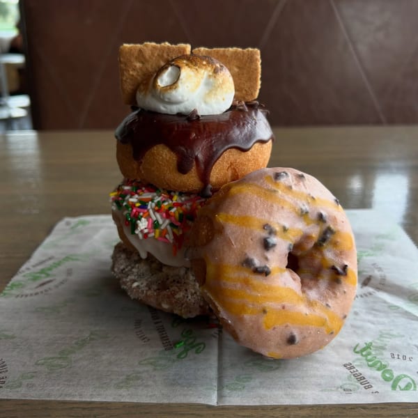 A stack of Joe Donut bakery donuts, including s'mores, sprinkle, and chocolate chip flavors.